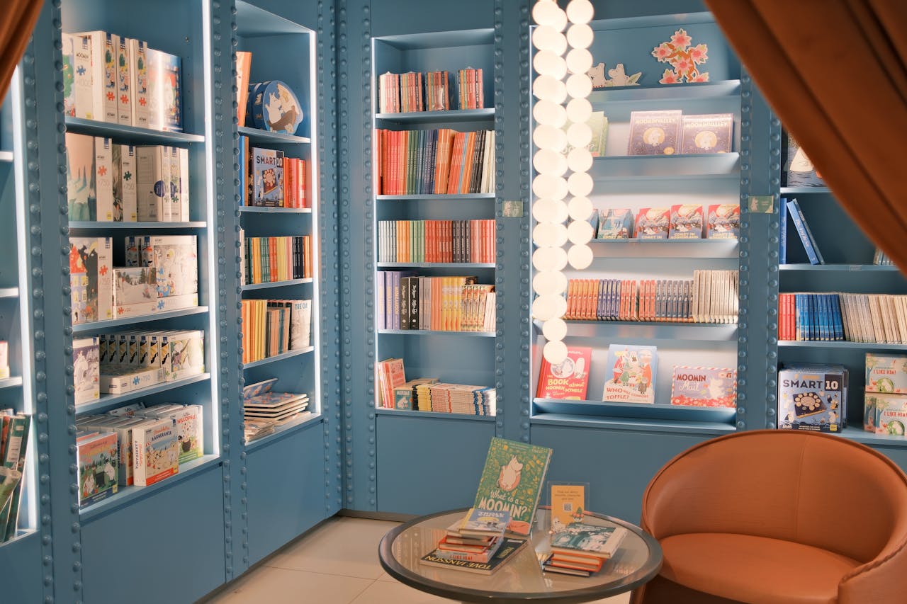 A bright children's bookstore featuring blue shelves filled with colorful books.