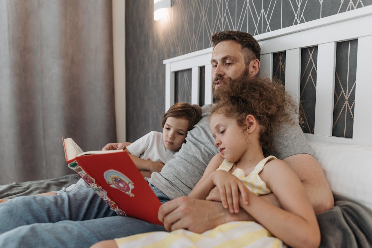 A father reading a storybook to his kids at bedtime, creating a cozy family moment.